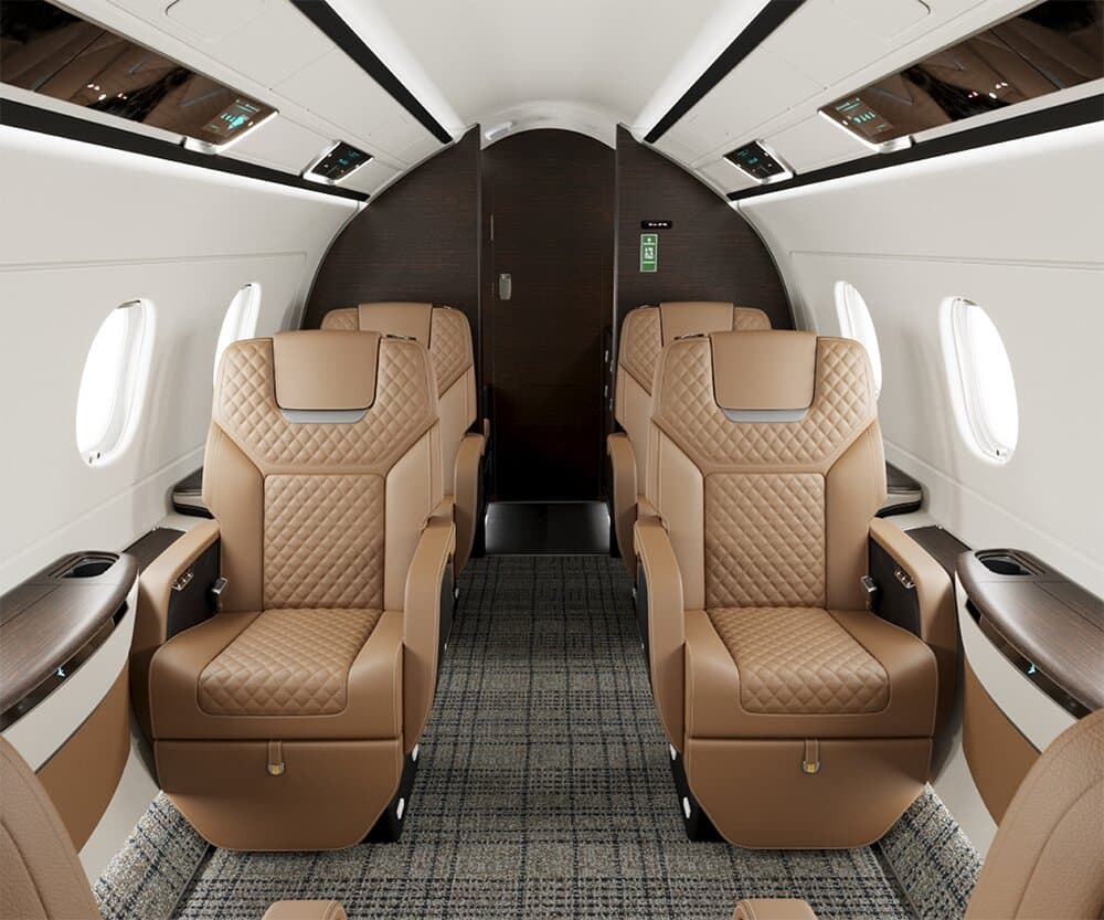 Four quilted tan seats facing each other in a jet cabin, dark wood panelling beyond them.