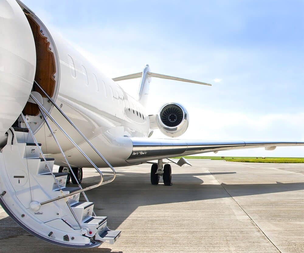 A white jet on the apron with its airstair down, wing and engine stretching away under a clear sky.